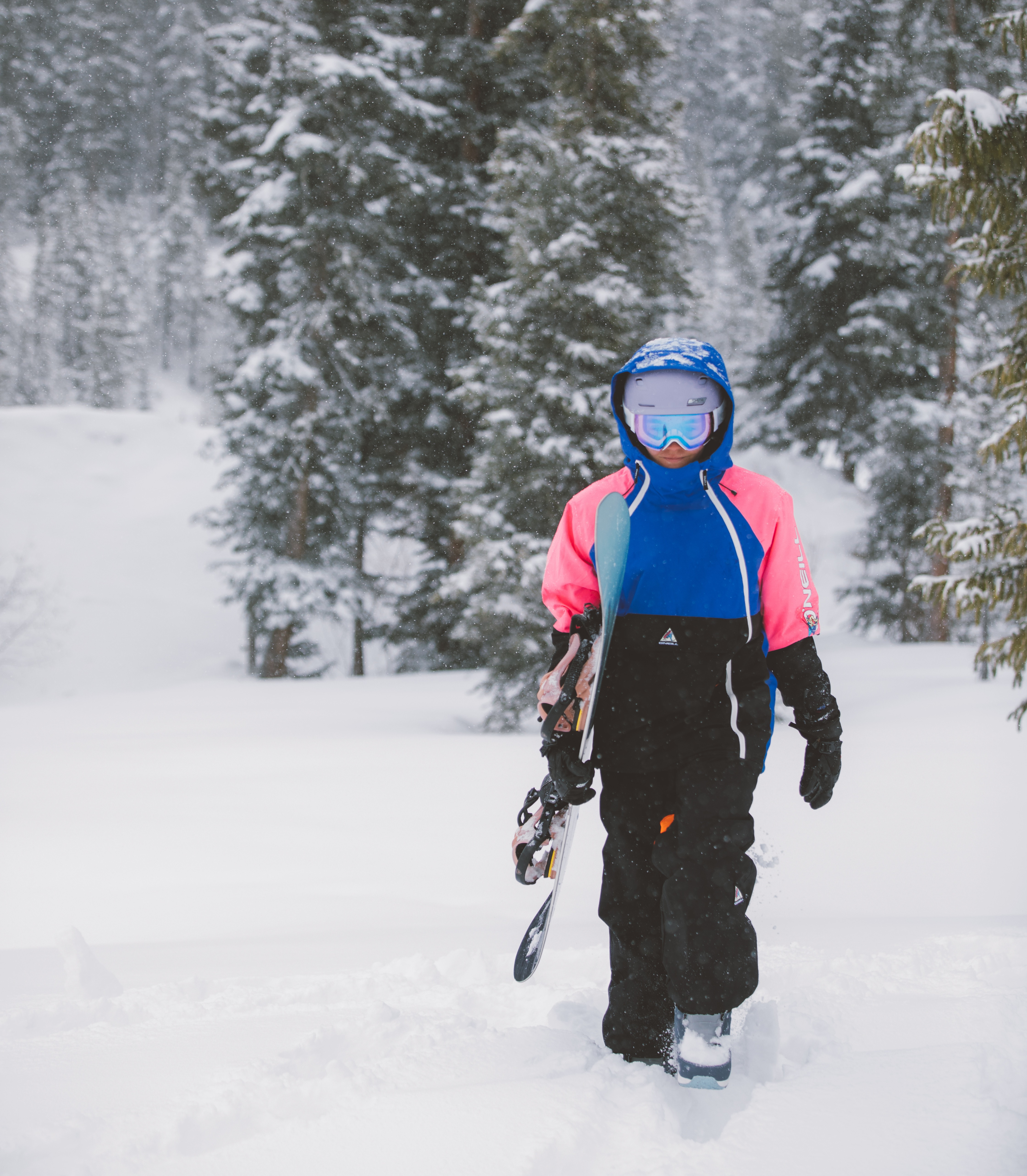 Woman walking through the snow carrying a snowboard